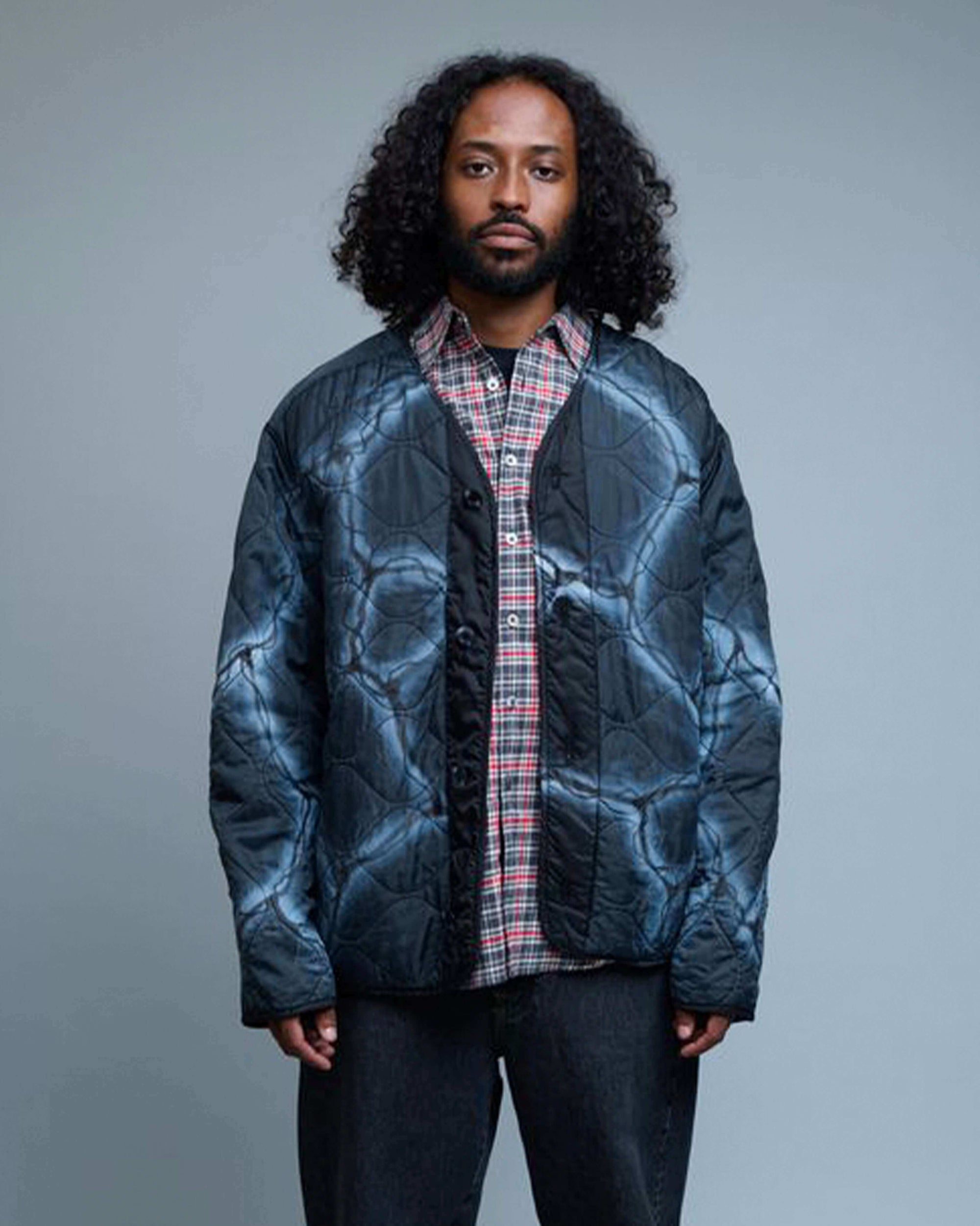 Model wearing Travis Spinks Custom Painted Combat Liner quilted jacket in nylon ripstop fabric.