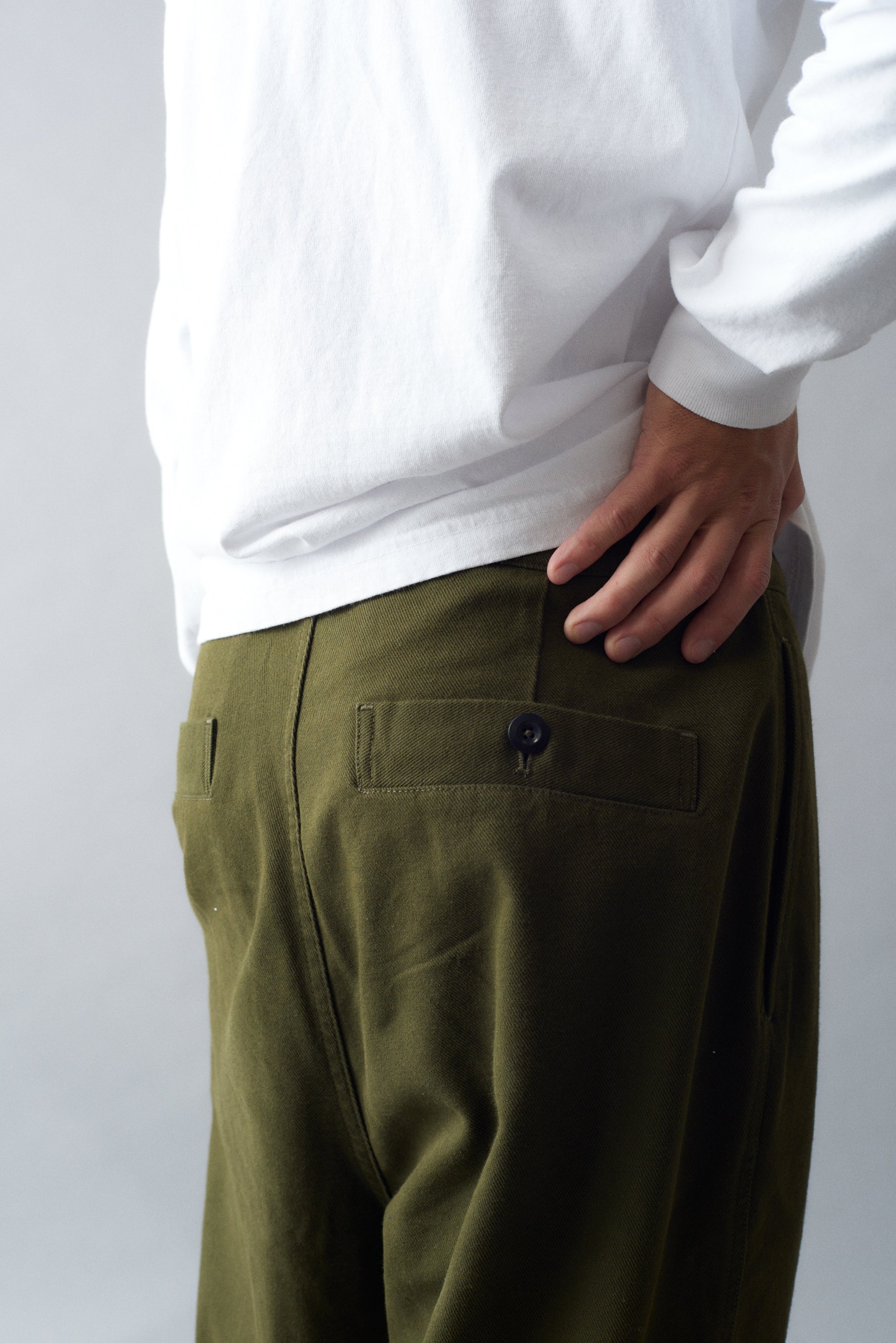 Side view of the MHL Cotton Wool Drill Slide Adjuster Trouser in olive green, showcasing button back pocket and belt details.