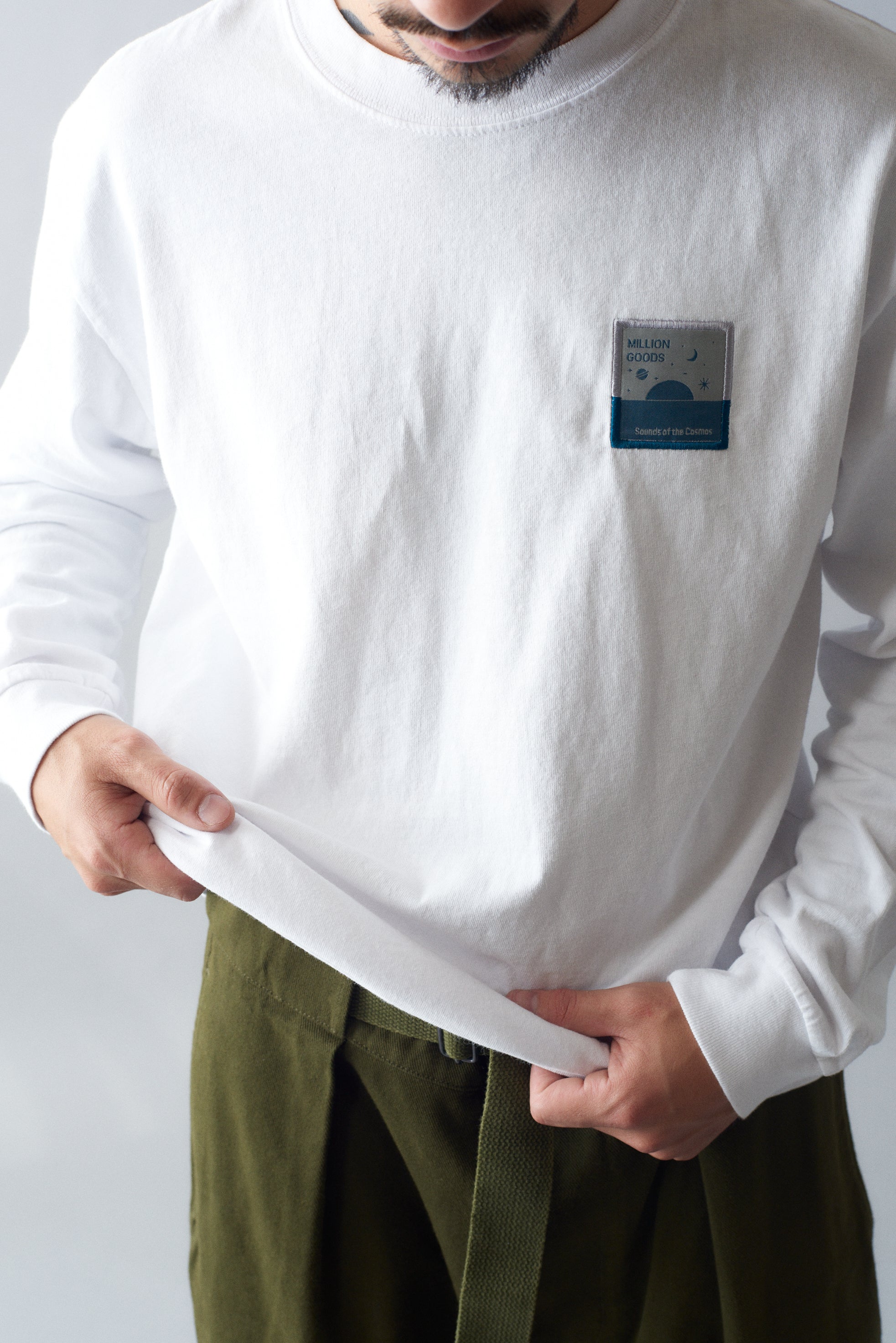 Man wearing a white long-sleeve shirt and green MHL Cotton Wool Drill Slide Adjuster Trousers.