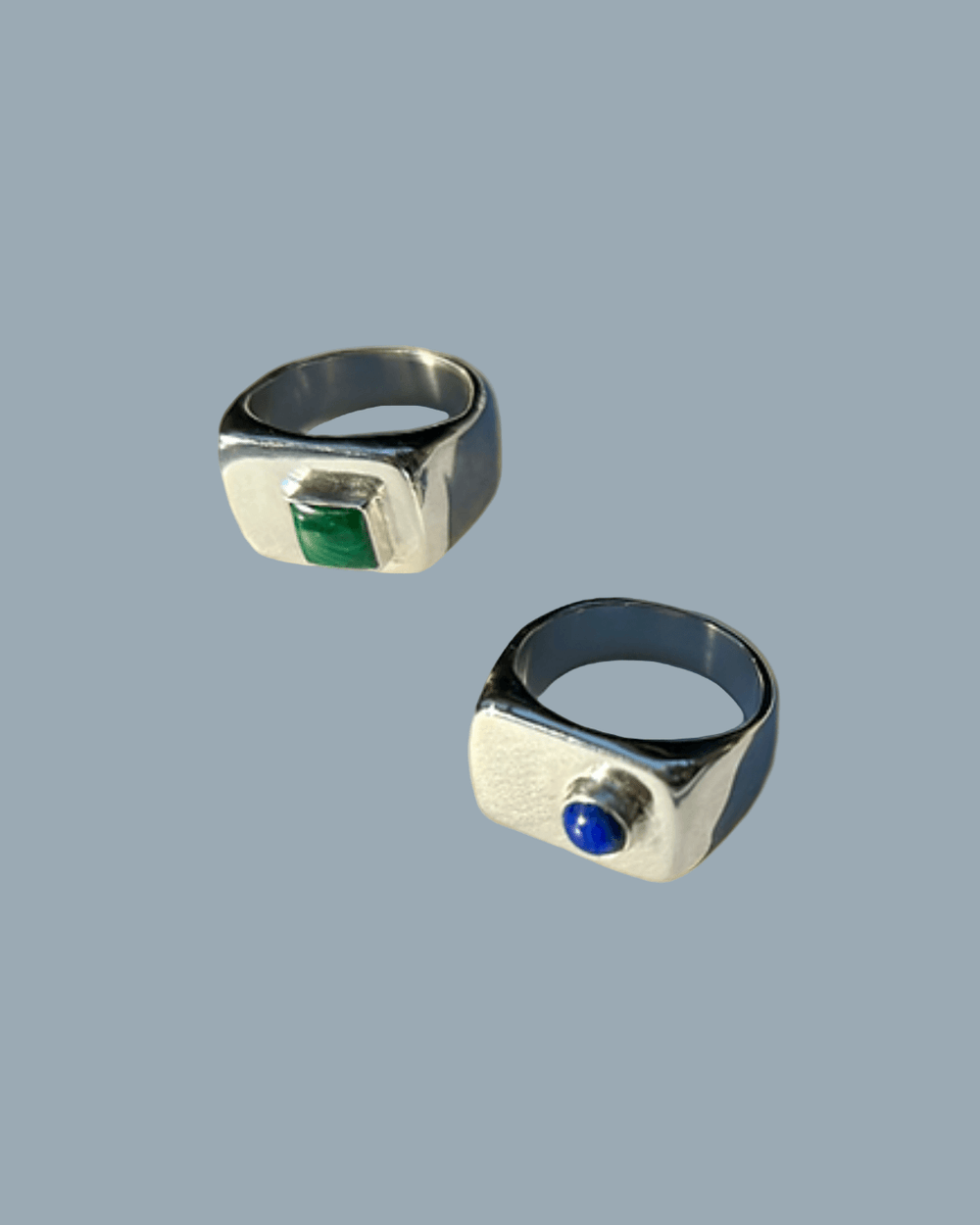 Two silver rings with gemstones on a gold background