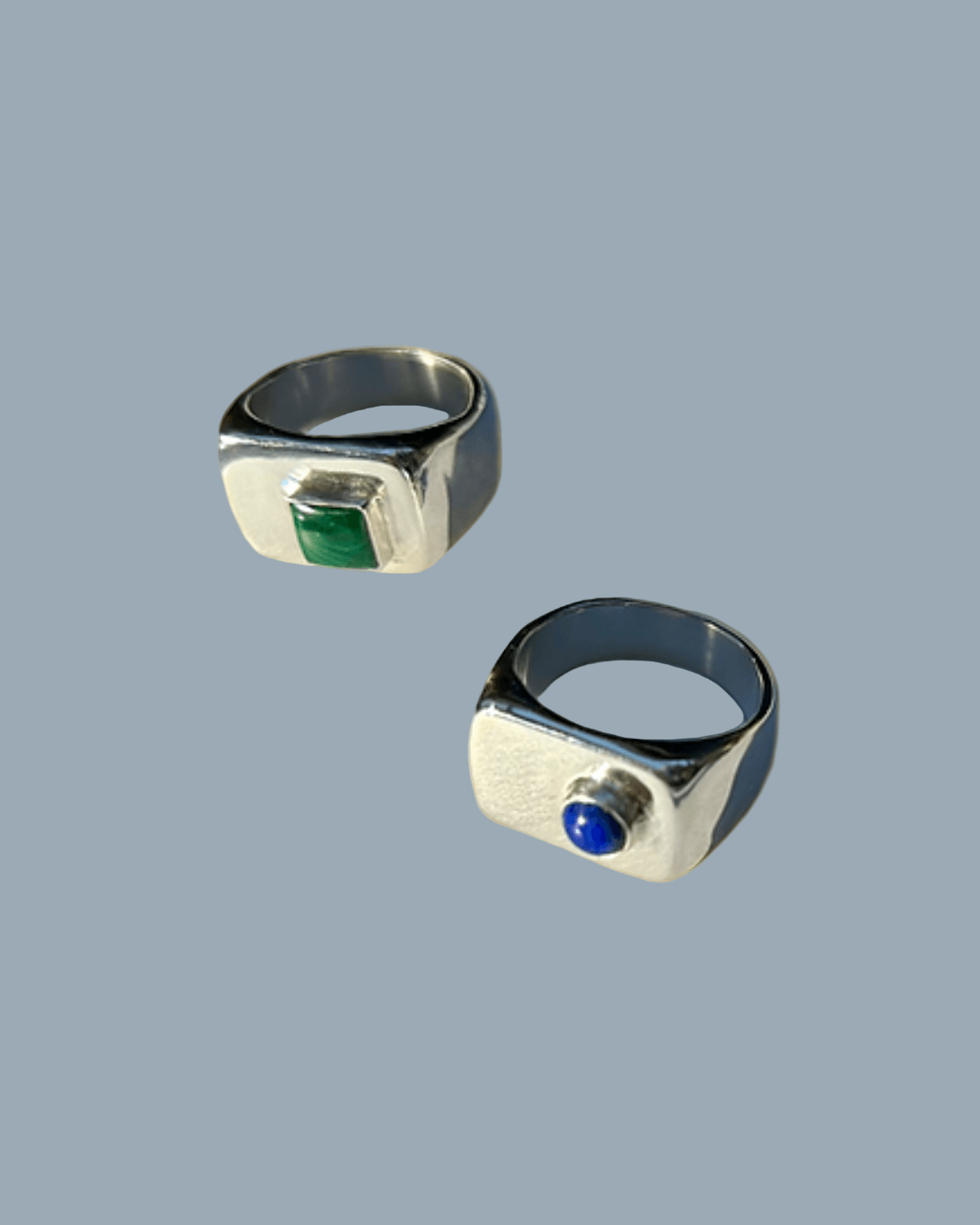 Two silver rings with gemstones on a gold background