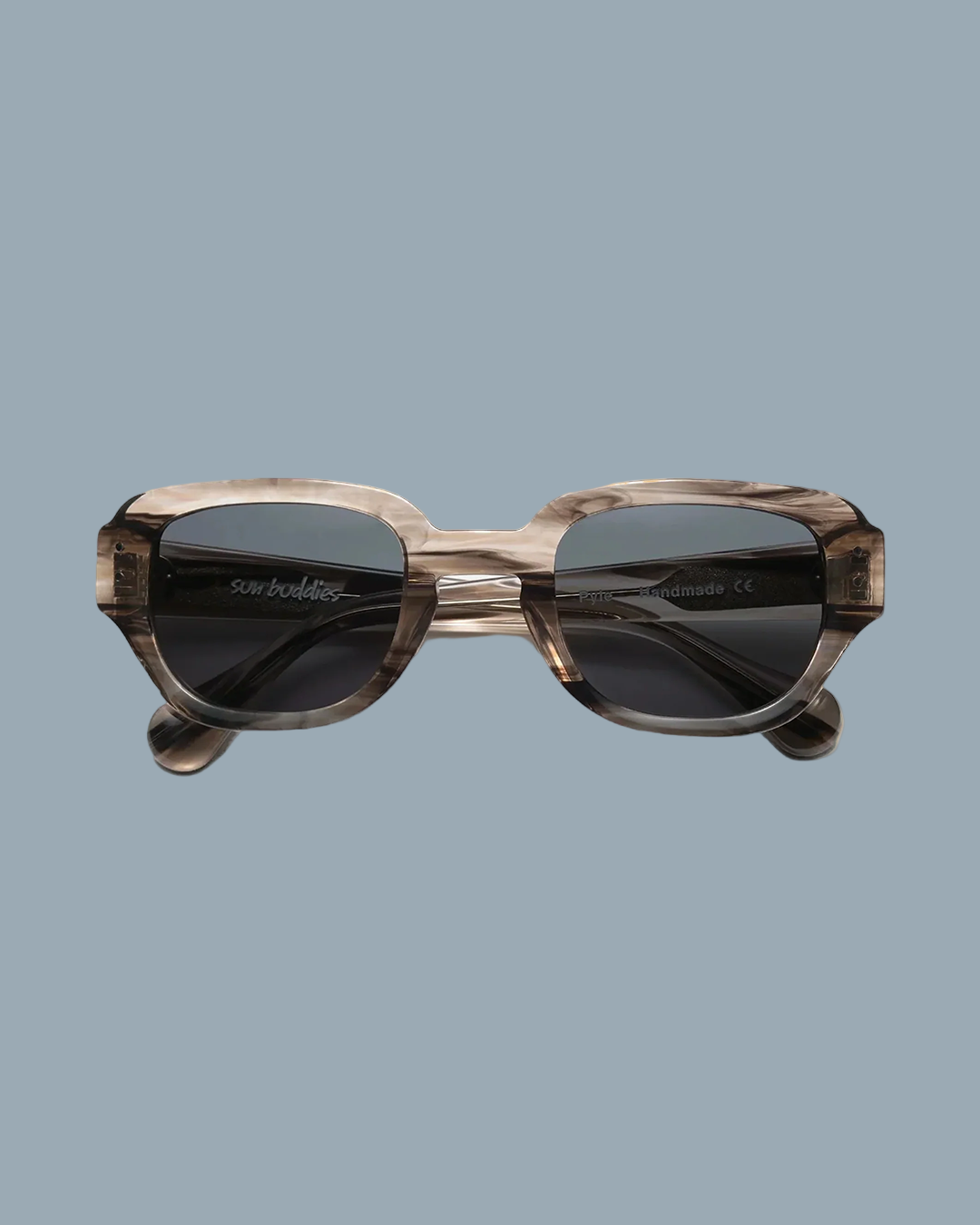 A pair of sunglasses with a geometric frame made of acetate, displayed against a beige background.